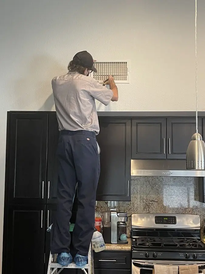 Technician inspecting an air vent during HVAC service in South Kingstown